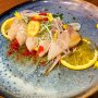 “Waar eet je goede sushi in Rotterdam?” Die vraag krijg ik bijna elke week wel en is verdacht lastig te beantwoorden. De rolls die zijn er wel bij de diverse Clubs, bij Yama eet je de lekkerste, maar moet je wachten tot 2020 en all you can eat durf je niet iedereen aan te raden. Dus het was goed dat Kyatcha kwam. Eerst verstopt in de Foodhallen en nu (ook) sinds kort naast de kubuswoningen op de Groenendaal. Omakase is het idee, ofwel je laat de chef beslissen, 3, 4 of 5 gangen, maar je kunt ook van het menu bestellen. Niet alleen puike rolls en zelfs zijdezacht vlees, maar ook veel rauwe vis, naast sashimi ook de Peruaanse variant tiradito, die je hier op de foto ziet van hamachi (een zusje van de tonijn) met sinaasappel, honing, shiso soja, jalapeno en sjalotjes. Bijna alle gangen zijn zo kleurrijk, complexe smaken, met vaak licht-zoet en umami als boventoon. 
We hebben er een verdomd goed adres voor sushi - in de brede zin van het woord - bij in Rotterdam en gelukkig nog bij mij om de hoek ook. 
#debuikvanrotterdam #sushi #sashimi #tiradito